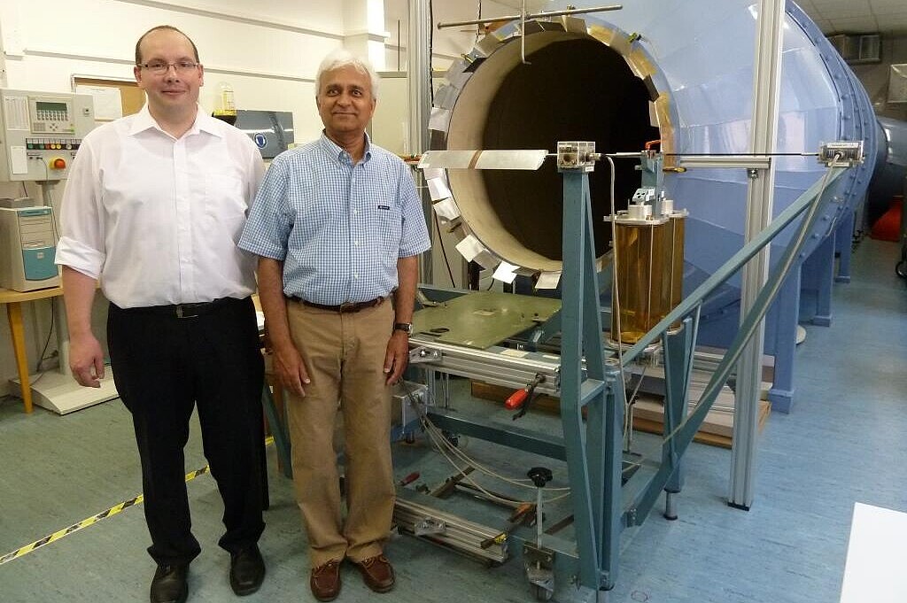 Two male professors in front of a wind tunnel