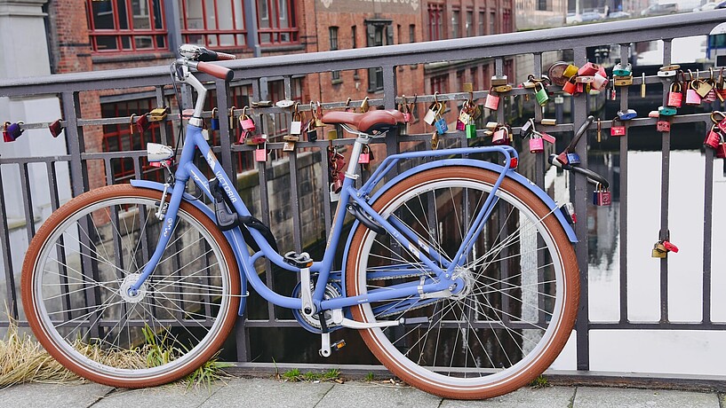 Blaues Damenfahrrad lehnt an ein Brückengeländer